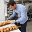 Un empleado colocando las empanadas recién horneadas en las tablas de presentación en uno de los establecimientos comerciales de Malvón. Firma: Malvón