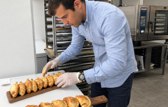 Un empleado colocando las empanadas recién horneadas en las tablas de presentación en uno de los establecimientos comerciales de Malvón. Firma: Malvón