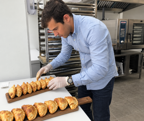 Un empleado colocando las empanadas recién horneadas en las tablas de presentación en uno de los establecimientos comerciales de Malvón. Firma: Malvón